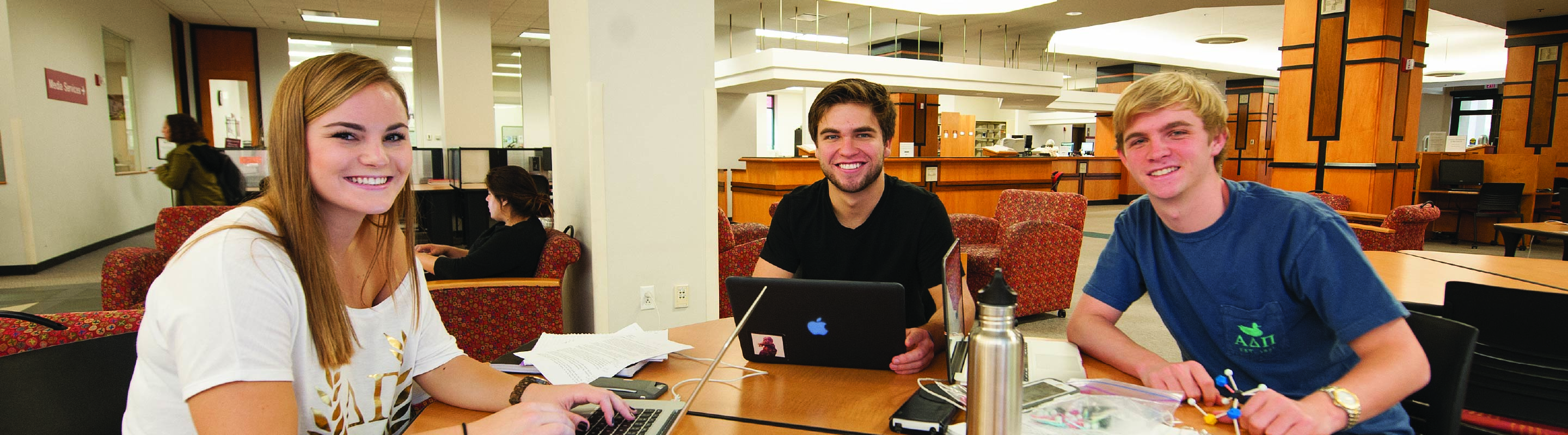 Three Honor Students smiling towards the camera in the library